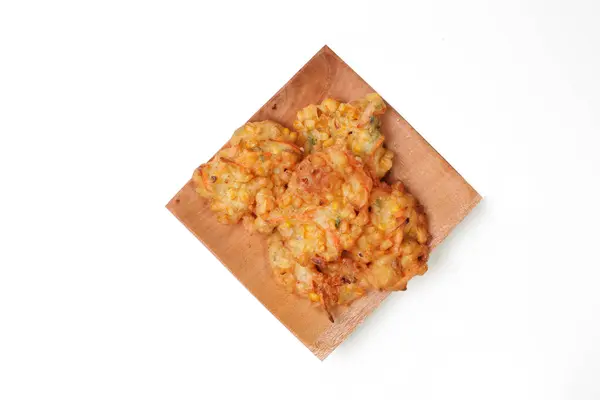 stock image Bakwan Jagung or Dadar Jagung or Dadar Jagung Manado, is Manadonese style of corn fritters. Indonesian snack made from corn and flour. Served on a wooden plate. White background. good for article