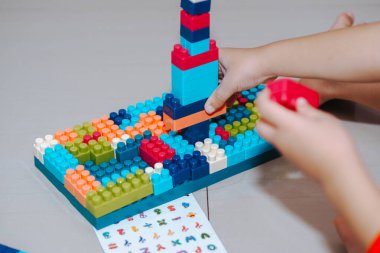 Bir çocuğun ellerinin tuğlayla oynaması, küçük çocukların plastik blokla bir şey inşa etmesi.