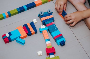 Bir çocuğun ellerinin tuğlayla oynaması, küçük çocukların plastik blokla bir şey inşa etmesi.
