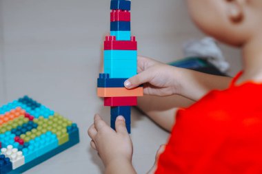 Bir çocuğun ellerinin tuğlayla oynaması, küçük çocukların plastik blokla bir şey inşa etmesi.
