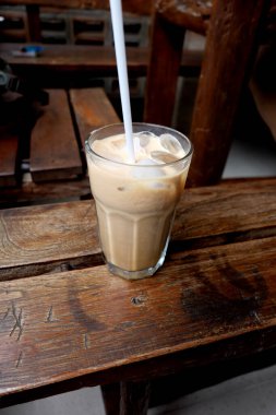 Tahta bir masada, bardakta sütlü kahve.