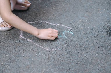 Garaj yolunda tebeşirle resim yapan bir çocuk.