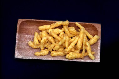 Siyah arka planda izole edilmiş ahşap bir tabakta peynirli cips.