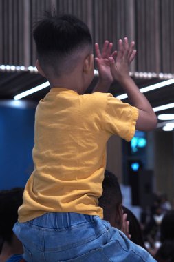 Arkadan görüldü. Çocuk babasının omuzlarında taşınır.