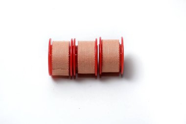 Beyaz arka planda üç rulo tıbbi yapıştırıcı izole edilmiş.