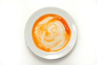 Beyaz tabak dökülmüş kırmızı sos gösteriyor.