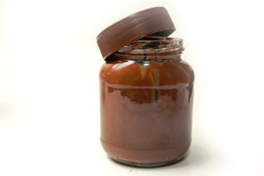 Yandan görünen çikolata serpiştirilmiş kavanoz, kapağı açık, beyaz arka planda izole.