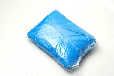 Beyaz arka planda izole edilmiş küçük paketler halinde katlanmış plastik yağmurluk