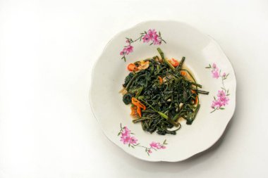 Kızarmış su ıspanağı ya da sabah zaferi ya da lahana, tabakta, beyaz arka planda izole edilmiş.