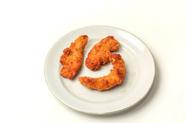 Bir tabakta üç parça snitzel, beyaz arka planda izole edilmiş.