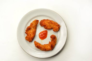 Bir tabakta üç parça snitzel, beyaz arka planda izole edilmiş.