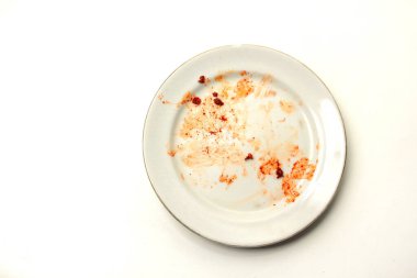 Beyaz arka planda izole edilmiş baharatlı soslu kirli bir tabağın üst görüntüsü. Yiyecek atıkları ve temizliği temsil ediyor