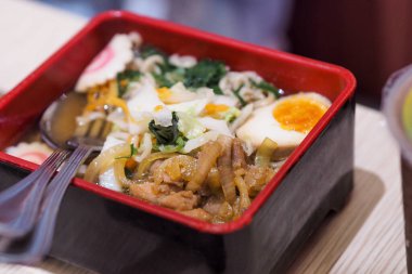 Bir kase ramen, yumurta ve biftek dilimleri.