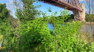 This video shows a view of the Hell Gate bridge in Bronx, NY.  The Hell Gate Bridge is a 1,017-foot steel through-arch railroad bridge in New York City.