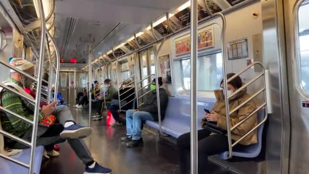 このビデオは ブルックリンからマンハッタンのダウンタウンに向かう地下鉄の電車の中で コロナウイルス時代にフェイスマスクを着用した人々の景色を示しています — ストック動画