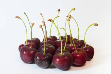 Beyaz bir arka planda olgun kirazlarla yıkanmış. Beyaz arka planda küçük bir grupta su damlaları olan kirazlar. Yemeye hazır yıkamadan sonra birkaç damla suyla birkaç kırmızı kiraz..