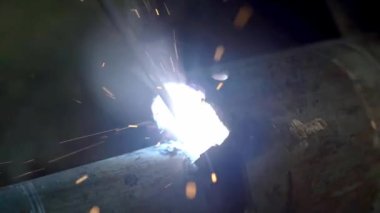 Bir adam bir kaynak makinesi ile çalışır. Küçük. Fabrikada kaynak çelik yapılar. Dışarı güzel kıvılcımlar.
