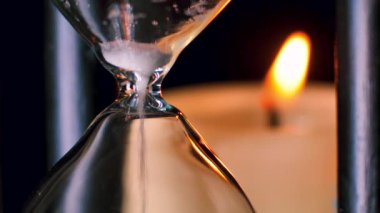 Yanan mumlu bir kum saati. Gebelik süresi çok az. Kum taneleri hızla aşağı düşer. Sinema tahılı, videoya yumuşak odaklanma