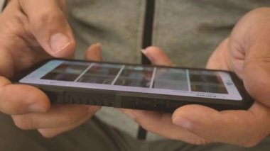 İnsan parmağı cep telefonundaki tomar sayfa uygulamasına dokunuyor. İnternet kütüphanesinde film ya da resim izlemek için film videoları taranıyor.