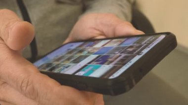 İnsan parmağı cep telefonundaki tomar sayfa uygulamasına dokunuyor. İnternet kütüphanesinde film ya da resim izlemek için film videoları taranıyor.