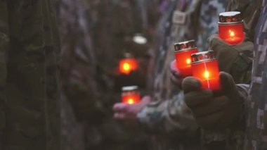 Unutmayalım diye hatırlatma günü. Mumlu Anma Günü. Anma mumları yanıyor. Askeri üniformalı Ukraynalı askerler ellerinde kırmızı mumlarla. Askeri geçit törenindeki askerler.