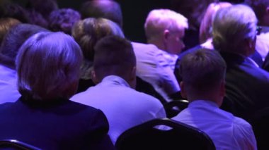 İnsanlar konser salonunda sırtlarını dönerek otururlar. Arkadan insan kafası..