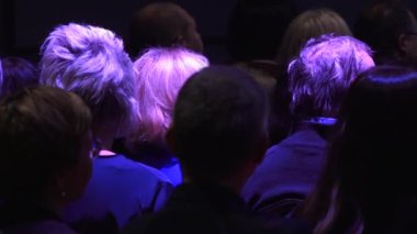 İnsanlar konser salonunda sırtlarını dönerek otururlar. Arkadan insan kafası..