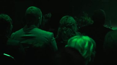 İnsanlar konser salonunda sırtlarını dönerek otururlar. Arkadan insan kafası..