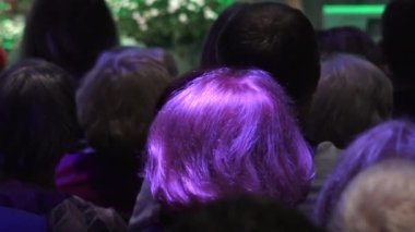 İnsanlar konser salonunda sırtlarını dönerek otururlar. Arkadan insan kafası..