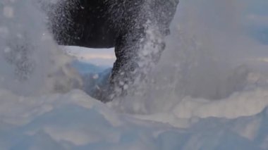 Çocuk çömeldi ve havaya kar attı. Karda ağır çekim. Kar elle atılıyor.