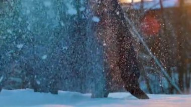 Çocuk çömeldi ve havaya kar attı. Karda ağır çekim. Kar elle atılıyor.