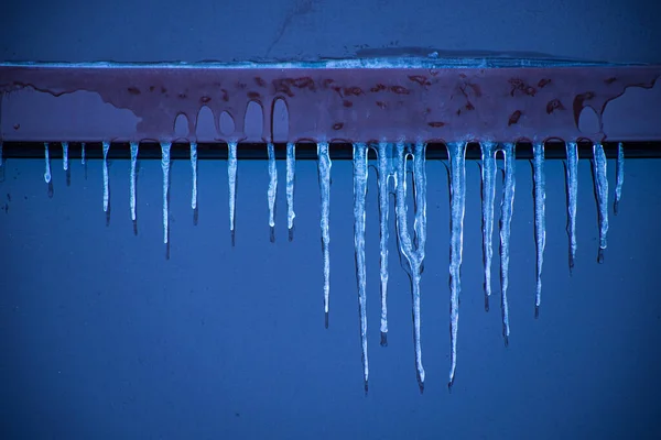 stock image Icicles near the window in winter. Glazed facade of the building with icicles. Ice on windows in cold weather. Soft focus on ice icicle