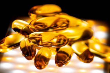 Kapsüllerde balık yağı ve aydınlatılmış bir arka plan. Yumuşak seçici odak