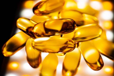 Kapsüllerde balık yağı ve aydınlatılmış bir arka plan. Yumuşak seçici odak