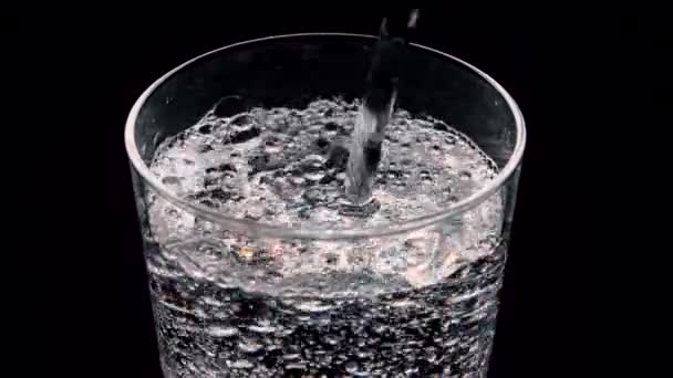 一杯在黑色背景上闪闪发光的水 气泡从玻璃杯里冒了出来 含气体的纯矿化水 — 图库视频影像