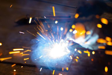 Metal kaynakçı, koruyucu ekipmanlı bir fabrikada çelik kaynakçıyla çalışıyor. Metal yapıların imalatı ve tamirat ve inşaat hizmetleri el işçiliği kavramına göre.