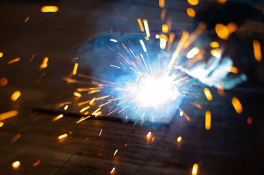 Metal kaynakçı, koruyucu ekipmanlı bir fabrikada çelik kaynakçıyla çalışıyor. Metal yapıların imalatı ve tamirat ve inşaat hizmetleri el işçiliği kavramına göre.