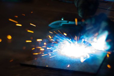 Metal kaynakçı, koruyucu ekipmanlı bir fabrikada çelik kaynakçıyla çalışıyor. Metal yapıların imalatı ve tamirat ve inşaat hizmetleri el işçiliği kavramına göre.