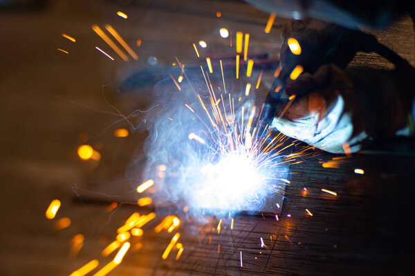 Металлосварщик работает со стальным сварщиком на заводе с защитным оборудованием. Производство металлоконструкций и ремонт и строительные услуги в соответствии с концепцией ручного труда.