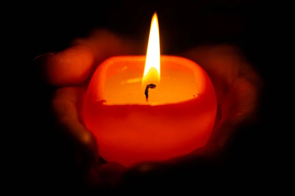 Burning candle man in your hands. Close-Up Of Hand Holding Illuminated Candle. Man with Burning Small Birthday Candle at black background for your element design. A burning candle flourishes.