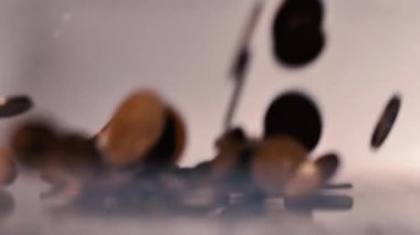 Para üstü masaya düşer. Yukardan gelen küçük bozuk paralar. Ağır çekimde masaya düşen az miktardaki avro sikkeleri. Bozukluklara yumuşak seçici odak