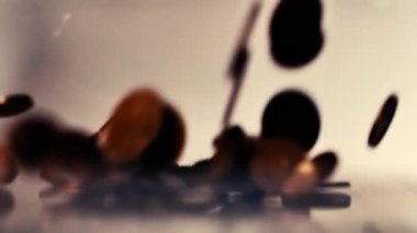 Para üstü masaya düşer. Yukardan gelen küçük bozuk paralar. Ağır çekimde masaya düşen az miktardaki avro sikkeleri. Bozukluklara yumuşak seçici odak