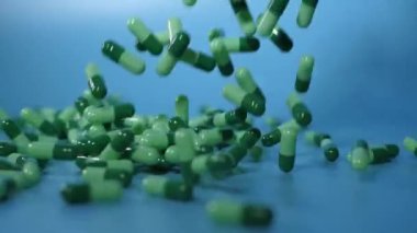 Green medicine capsules fall on a blue background. Waterfall from medicinal capsules. Medical concept overdose. A group of antibiotic pill capsules falling. Medicine and Pharmaceutical Business 