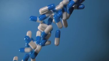 Blue medicine capsules fall on a blue background. Waterfall from medicinal capsules. Medical concept overdose. A group of antibiotic pill capsules falling