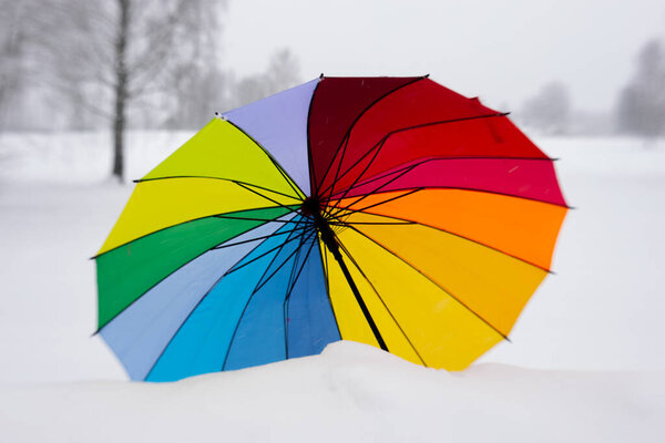 Цветной зонтик зимой на снегу. Зонтик только на снегу.