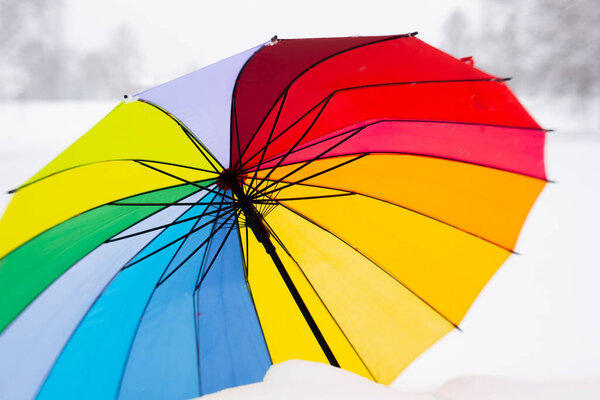 Цветной зонтик зимой на снегу. Зонтик только на снегу.