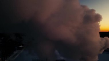 Kazan dairesinin bacasından duman yükseliyor. Gün batımında bacadan duman çıkıyor. Ekonomik ısınma krizi. Pahalı ısıtma. Odun parçaları şehri ısıtıyor..
