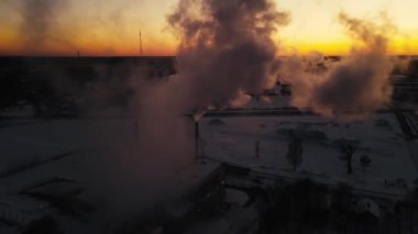 Kazan dairesinin bacasından duman yükseliyor. Gün batımında bacadan duman çıkıyor. Ekonomik ısınma krizi. Pahalı ısıtma. Odun parçaları şehri ısıtıyor..