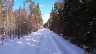 Kışın orman yolunda uçan bir dronun hava görüntüsü. Araba karla kaplı bir yolda gidiyor.