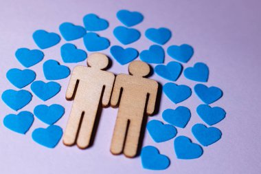 Erkek aşkı LGBT. Eşcinsel aile ikonları. İki eşcinsel erkek çifti. Erkek çift el ele tutuşuyor. Kağıt mavisi kalpleri olan tahta insanlar.